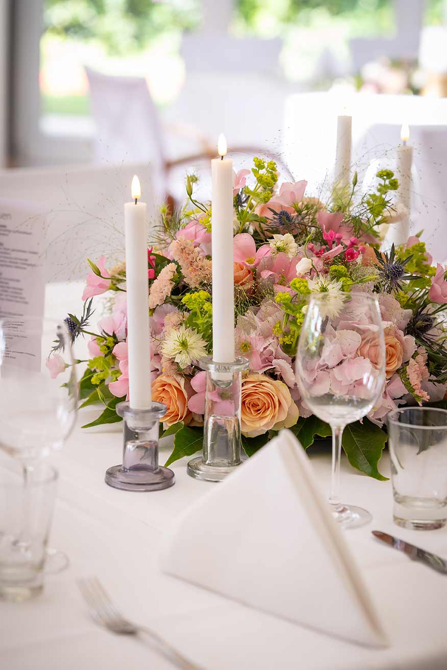 Leuchtturm_Harburg_Hochzeit_Tischdeko Stimmungsvolle Tischdekoration mit Blumengesteck und Kerzen für eine Hochzeit im Leuchtturm Harburg